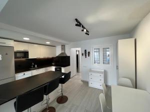 a kitchen with white cabinets and black counter tops at Secret Surf House. Casa de playa. in Playa del Hombre +7 photos