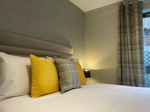 1 dormitorio con cama blanca y almohadas amarillas en York Staycation with Free Parking en York