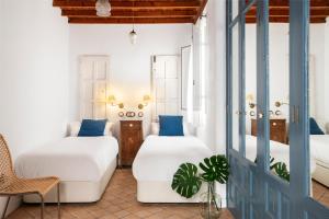 Habitación con 2 camas, silla y puerta en Magno Apartments Vírgenes Luxury House en Sevilla