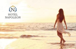a woman in a white dress walking on the beach at Hotel Napoleon in Cesenatico