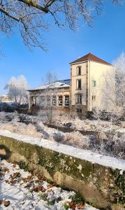 an old building with snow in front of it at La Ferblanterie in Rambervillers