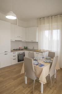 una cucina con tavolo e sedie e una cucina con armadietti bianchi di La Casa dei Racconti a Castelraimondo