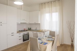a kitchen with white cabinets and a table with chairs at La Casa dei Racconti in Castelraimondo