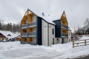 a building in the snow with a fence at Apartmány Jarmilka in Bedřichov