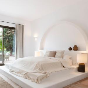 - une chambre blanche avec un grand lit et une fenêtre dans l'établissement Finca La Familia Naranja, à Coín