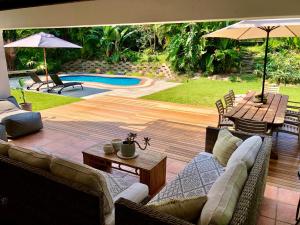 a patio with couches and tables and a pool at Woodlands Beach Villa in Southbroom