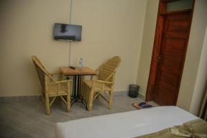 a room with a table and chairs and a television at Fort Suites in Fort Portal