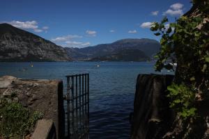 a gate to a body of water with mountains at Estivo Premium Deluxe mobile homes on Camping Del Sole Village in Iseo