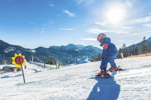un niño pequeño está esquiando por una pista cubierta de nieve en Das Ferienhaus in Achenkirch en Achenkirch