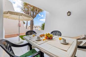 a table with a bowl of fruit and an umbrella at Home2Book Sunny Apt Pool & Beach, Costa Teguise in Costa Teguise