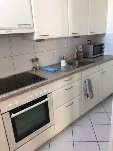 a kitchen with white cabinets and a sink and a stove at Ganze Wohnung mit Balkon,schöne Aussicht,Küche,Bad,Wifi in Basel