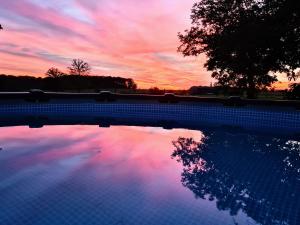 un reflejo de una puesta de sol en una piscina en Gîte La Besse, Claudon en Claudon
