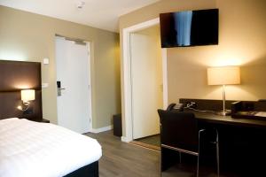 a hotel room with a bed and a desk with a telephone at Hotel Roermond Next Door in Roermond