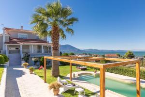 a house with a swimming pool and a palm tree at Mary's Home in Néa Artáki