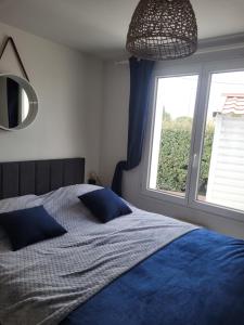 a bedroom with a bed with blue sheets and a window at Sérénité Marine : Maison en Bord de Mer à Notre Dame de Monts in Notre-Dame-de-Monts