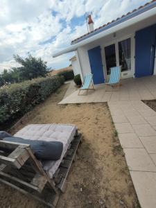 a patio with two blue chairs and a house at Sérénité Marine : Maison en Bord de Mer à Notre Dame de Monts in Notre-Dame-de-Monts