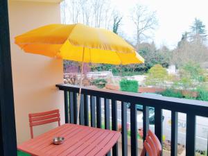 une table rouge avec un parasol jaune sur un balcon dans l'établissement Borda -41- au coeur des Thermes Borda, à Dax