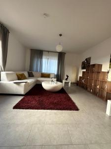 a living room with a white couch and a red rug at Ferienwohnung Eira in Bonerath