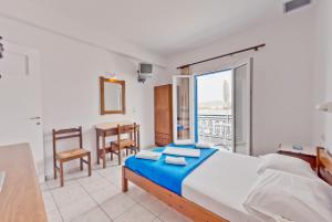 a bedroom with a bed and a table and a window at Paris Rooms in Antiparos Town