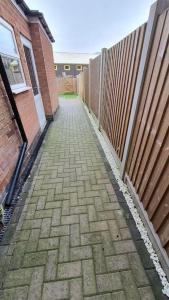a brick sidewalk next to a fence next to a building at Contractors-City Centre-Parking-Sleeps 9 -Smart TV, 2 Toilets! in Coventry