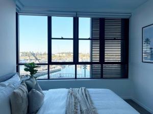 Cette chambre comprend un lit et une grande fenêtre. dans l'établissement Luxury Apartment in Shell Cove, à Shellharbour