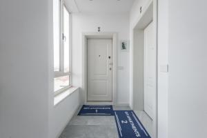 a hallway with a white door and a blue rug at Sky Apartments in Durrës