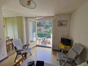sala de estar con sillas, TV y balcón en Appartement Amélie les Bains au pied des THERMES, en Amélie-les-Bains-Palalda