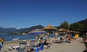 a group of people on a beach with chairs and umbrellas at Estivo Premium Deluxe mobile homes on Camping Del Sole Village in Iseo