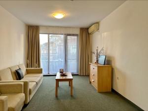 a living room with a couch and a tv and a table at Menada Apartments in Marina Cape in Aheloy