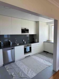 a kitchen with white cabinets and a rug at Apartamento vista mar in Labruge