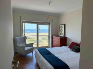 a bedroom with a bed and a chair and a window at Apartamento vista mar in Labruge