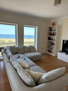uma sala de estar com um grande sofá em frente a duas janelas em Apartamento vista mar em Labruge
