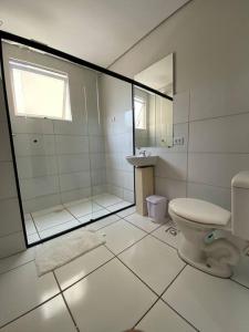 La salle de bains blanche est pourvue d'une douche et de toilettes. dans l'établissement Apartamento em Várzea Grande MT, à Várzea Grande