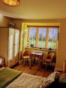 a bedroom with a table and chairs and windows at Rosegarth Bed and Breakfast in Marton