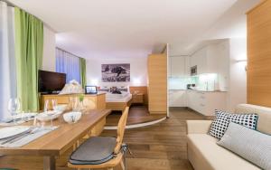 uma sala de estar com uma mesa e um sofá em Avita - suites to relax em Ortisei