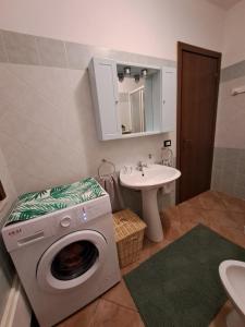 ein Badezimmer mit einer Waschmaschine und einem Waschbecken in der Unterkunft Casa vacanze sole e mare in Porto Pino