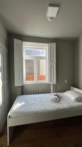 un letto in una camera da letto con finestra di A Beira Hostel ad Aveiro
