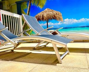 two lawn chairs and an umbrella on the beach at L'Eskale Guyane in Montjoly