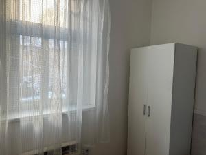 a window with white curtains next to a white cabinet at Penzion Sokolov 1 in Sokolov
