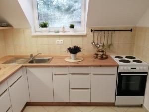a kitchen with white cabinets and a sink and a stove at Rekreační domek Pod Lipou in Škrdlovice +22 photos
