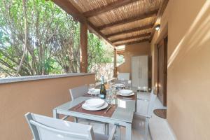 a dining room with a table and chairs on a balcony at White Sand House in Marina di Portisco