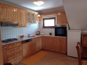- une cuisine avec des placards en bois et un réfrigérateur blanc dans l'établissement Apartman Centar Fužine, à Fužine