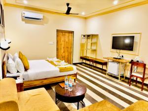 Udai Valley Resort- Top Rated Resort in Udaipur with mountain view في أودايبور: غرفة فندق بسرير وتلفزيون