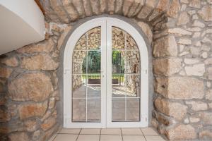 an arched glass door in a stone wall at Villa Karlo - Sabljići - Island of Krk - traditional stone villa with pool in Sveti Anton