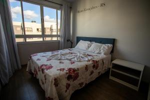 a bedroom with a bed with a flowered blanket and a window at WineAP - Pensando em Vinhos in Bento Gonçalves