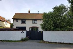 a white house with a black gate in front of it at The Flat at Conway House in Overstrand