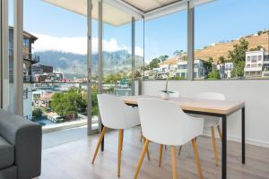 a dining room with a table and white chairs and large windows at The Quarter Luxury Apartments in Cape Town