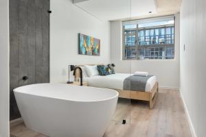 a white bath tub in a bathroom with a bed at The Quarter Luxury Apartments in Cape Town