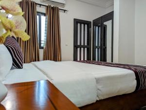Schlafzimmer mit einem weißen Bett und Holzboden in der Unterkunft Les Ombrelles Appart'Hotel in Cotonou