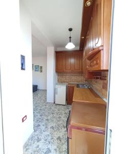 eine Küche mit Holzschränken und einem weißen Kühlschrank in der Unterkunft RINA'S Apartment in Berat